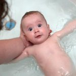 кроха плавает на спинке в ванне