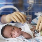 Новорожденного осматривает врач